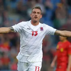 Jugador de la luxemburgo seleccion celebra un gol, con el número 13 en su camiseta blanca.