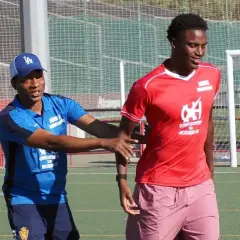 Entrenador da instrucciones a un joven cadete de fútbol en el campo.