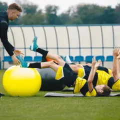 Entrenador supervisa a jóvenes futbolistas en un circuito de resistencia física.