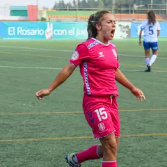 Jugadora de fútbol femenino con camiseta rosa y número 15, celebrando un gol. Las águilas femenino luchan en el campo.