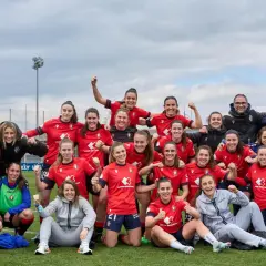 Equipo de fútbol femenino celebra su clasificación. Jugadoras sonrientes y con puños en alto, junto a su cuerpo técnico.