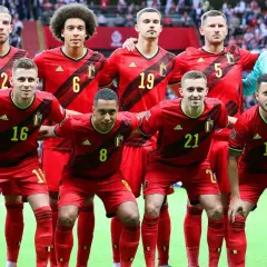 Jugadores del Bélgica FC posan juntos, luciendo sus uniformes rojos y amarillos.