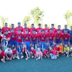 Equipo de fútbol posa para una foto grupal, con adultos y niños. Los **ffcm resultados preferente** son evidentes en la unidad del equipo.