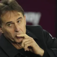 Entrenador de Qatar, con la mano en la barbilla, pensativo, sentado en un banco.