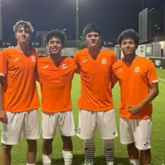 Cuatro jóvenes futbolistas del Olímpico de Villarrobledo posan sonrientes en el campo de césped artificial.
