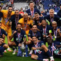 Jugadores del PSG celebran con trofeo y medallas tras ganar la liga francesa de fútbol.
