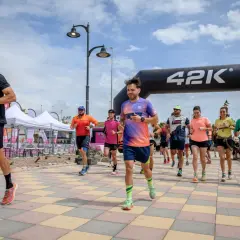 Corredores inician una carrera bajo un arco de 42K. La pregunta de cuanto dura un calentamiento se responde con la energía de estos atletas.