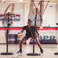 Jugador de baloncesto practica sus tiros libres rodeado de maniquíes de defensa.