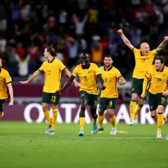 Jugadores de la Australia seleccion celebran con euforia en el campo de juego, con los brazos en alto y sonrisas de victoria.