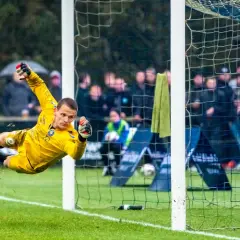 Portero amarillo se lanza en el aire para detener un balón. Los porteros pequeños son ágiles y valientes.