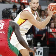 Jugador de baloncesto con el balón en mano, listo para su primera canasta de baloncesto, defendido por un oponente.