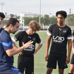 Entrenador explica a jóvenes futbolistas cómo trabajar la mente en el campo.