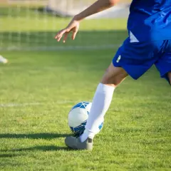 Jugador en pleno entrenamiento de fútbol 7, a punto de chutar el balón en un campo de césped verde.