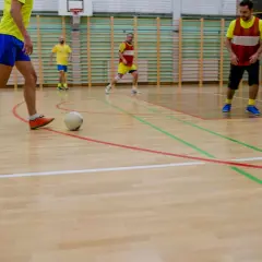 Jugadores realizan ejercicios individuales de fútbol sala en cancha de madera.