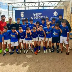 Equipo de fútbol infantil posa sonriente. El cartel de fondo anuncia "¡Siente el deporte!" y el logo del Ayuntamiento de San José.