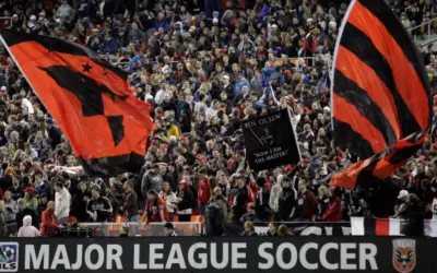 Aficionados ondean banderas rojas y negras en un partido de la liga futbol eeuu.