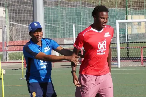 Entrenador da instrucciones a un joven cadete de fútbol en el campo.
