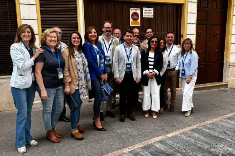 Grupo de personas sonriendo frente a un edificio. cf almaguer.
