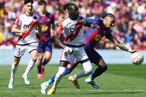Jugadores del Rayo Vallecano y Barcelona en acción. Un jugador del Rayo, con el dorsal 6, lucha por el balón.