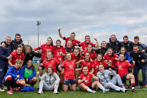 Equipo de fútbol femenino celebra su clasificación. Jugadoras sonrientes y con puños en alto, junto a su cuerpo técnico.