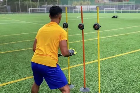 Portero entrenando para mejorar sus reflejos, reaccionando a luces en postes.
