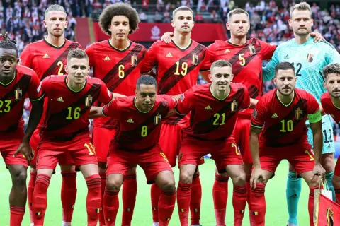 Jugadores del Bélgica FC posan juntos, luciendo sus uniformes rojos y amarillos.