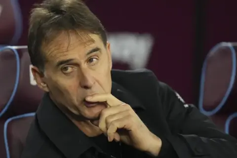 Entrenador de Qatar, con la mano en la barbilla, pensativo, sentado en un banco.