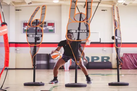 Jugador de baloncesto practica sus tiros libres rodeado de maniquíes de defensa.