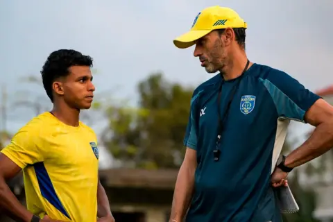 Entrenador habla con jugador joven en la liga india futbol.