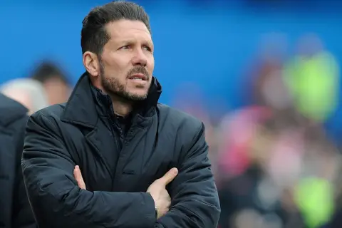Diego Pablo Simeone, con los brazos cruzados, mira atentamente el partido con una chaqueta oscura.
