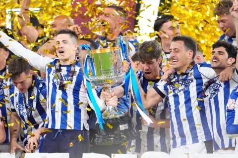 Jugadores celebran con la copa tras ganar la final Copa del Rey. Confeti dorado cae sobre ellos.