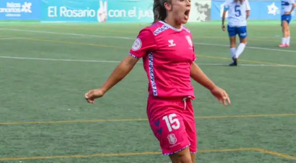 Jugadora de fútbol femenino con camiseta rosa y número 15, celebrando un gol. Las águilas femenino luchan en el campo.