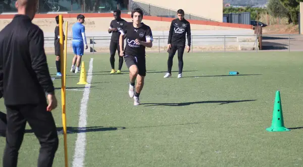 Jóvenes futbolistas realizan pruebas físicas en campo. Un entrenador de fútbol nivel 1 supervisa el entrenamiento.
