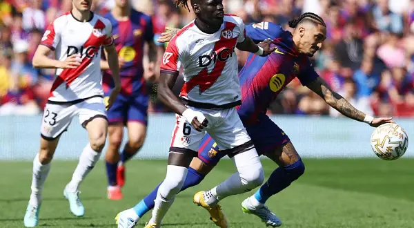 Jugadores del Rayo Vallecano y Barcelona en acción. Un jugador del Rayo, con el dorsal 6, lucha por el balón.