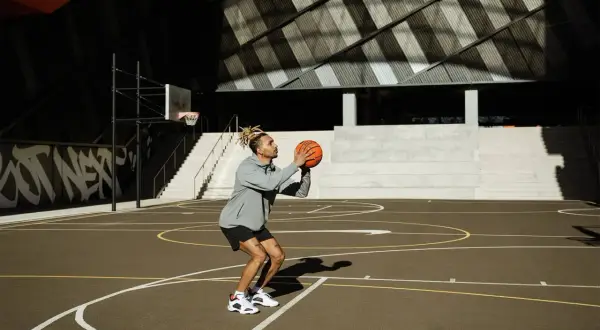 Hombre concentrado en un tiro libre de baloncesto en una cancha exterior.