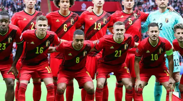 Jugadores del Bélgica FC posan juntos, luciendo sus uniformes rojos y amarillos.