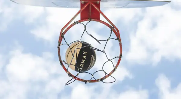 Un balón de baloncesto a punto de entrar en la canasta. La altura reglamentaria de a cuantos metros está la canasta de baloncesto del suelo es de 3.05 metros.