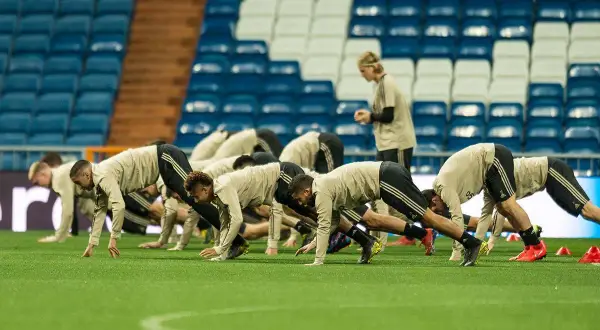 Jugadores de fútbol en posición de plancha durante el calentamiento.