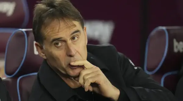 Entrenador de Qatar, con la mano en la barbilla, pensativo, sentado en un banco.