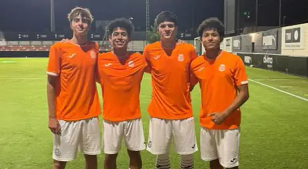 Cuatro jóvenes futbolistas del Olímpico de Villarrobledo posan sonrientes en el campo de césped artificial.