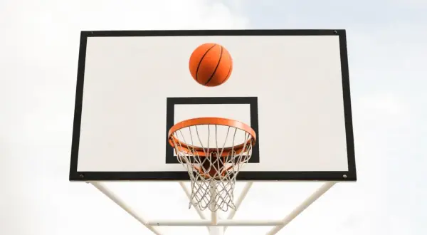 Balón de baloncesto naranja en el aire, a punto de entrar en la canasta. ¡Un tiro perfecto!
