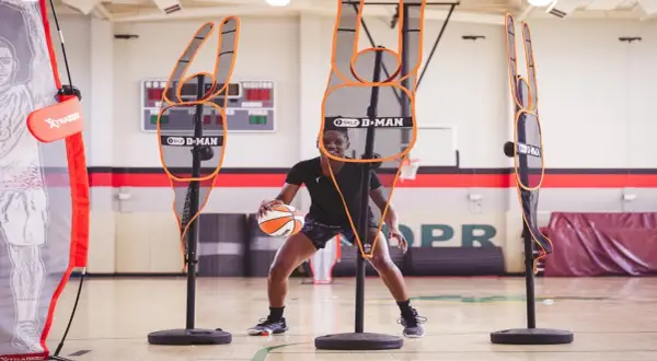 Jugador de baloncesto practica sus tiros libres rodeado de maniquíes de defensa.