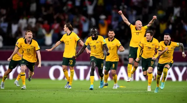 Jugadores de la Australia seleccion celebran con euforia en el campo de juego, con los brazos en alto y sonrisas de victoria.