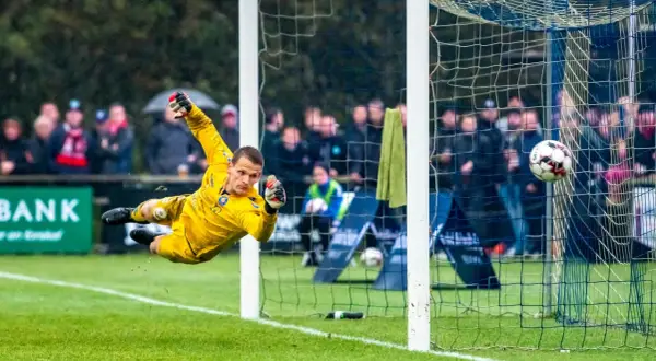 Portero amarillo se lanza en el aire para detener un balón. Los porteros pequeños son ágiles y valientes.