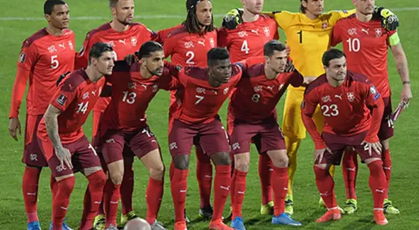 El equipo de fútbol suizo posa en el campo. Los jugadores lucen sus uniformes rojos, listos para el partido.