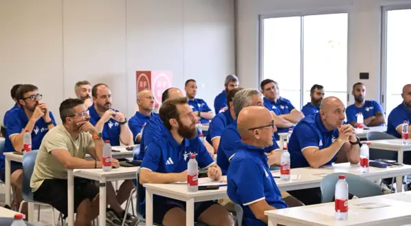 Un grupo de entrenadores España asiste a una charla en un aula, todos con polos azules.