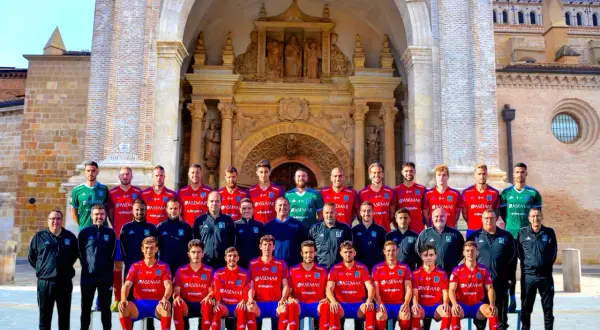 El equipo del Atlético Tarazona posa para una foto grupal frente a una fachada histórica.