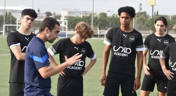Entrenador explica a jóvenes futbolistas cómo trabajar la mente en el campo.