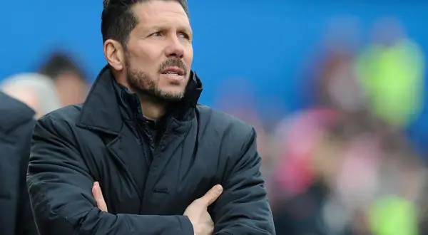 Diego Pablo Simeone, con los brazos cruzados, mira atentamente el partido con una chaqueta oscura.