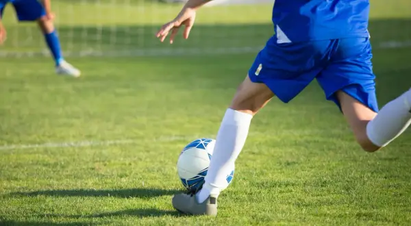 Jugador en pleno entrenamiento de fútbol 7, a punto de chutar el balón en un campo de césped verde.